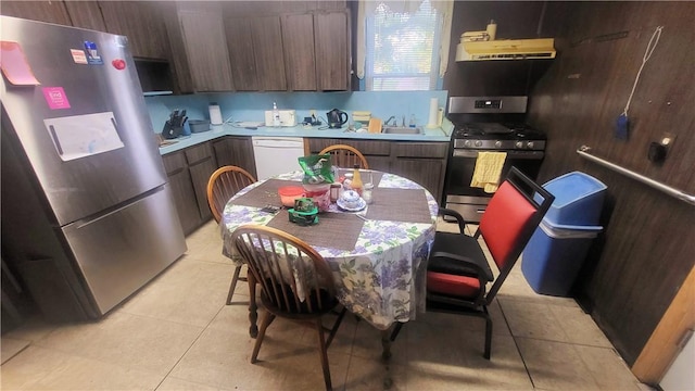 kitchen featuring dark brown cabinetry, stainless steel appliances, sink, exhaust hood, and light tile patterned floors