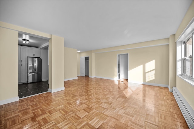 unfurnished living room with baseboard heating and light parquet flooring