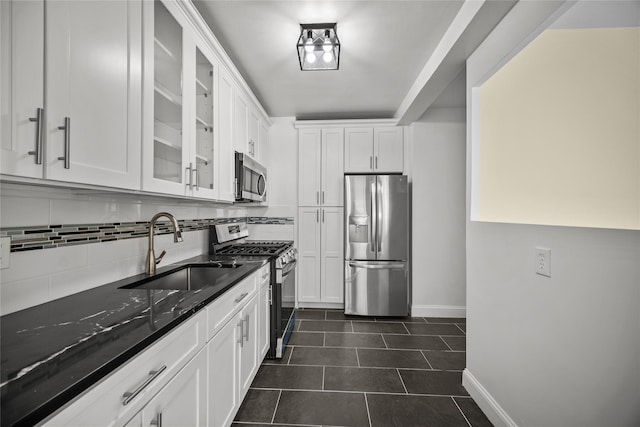 kitchen featuring dark stone counters, sink, white cabinets, and stainless steel appliances