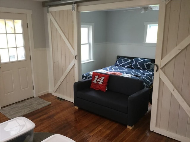 bedroom featuring a barn door, dark hardwood / wood-style floors, and multiple windows