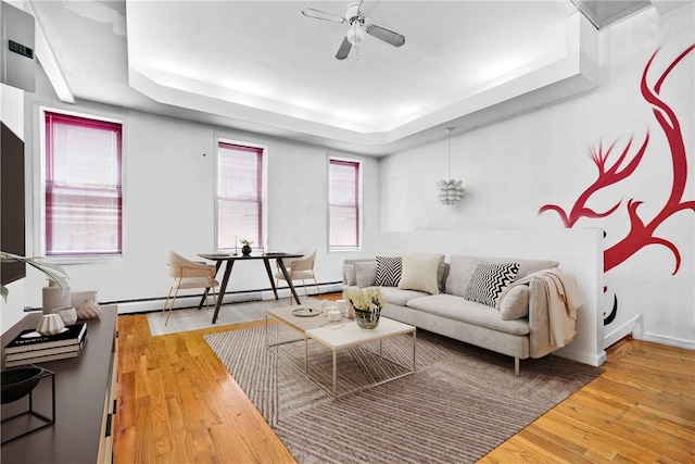 living room featuring hardwood / wood-style flooring, a raised ceiling, a wealth of natural light, and a baseboard heating unit