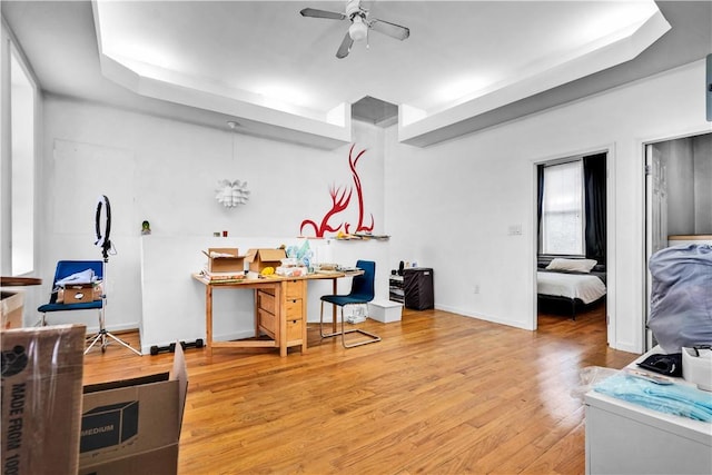 interior space with wood-type flooring, a raised ceiling, and ceiling fan