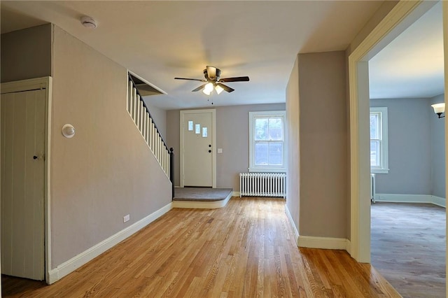 entryway featuring ceiling fan, radiator heating unit, and light hardwood / wood-style flooring