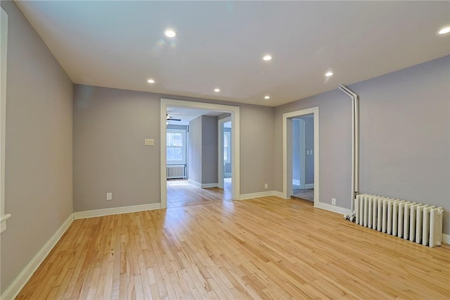 empty room with radiator heating unit and light hardwood / wood-style flooring