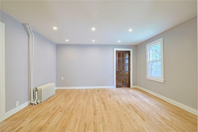 spare room featuring light wood-type flooring and radiator heating unit