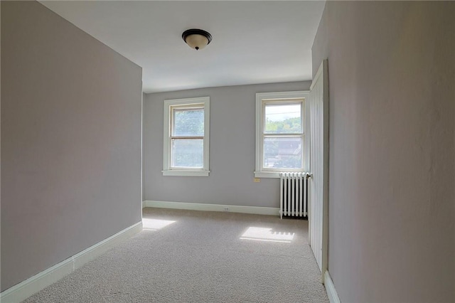 empty room featuring radiator heating unit and light colored carpet