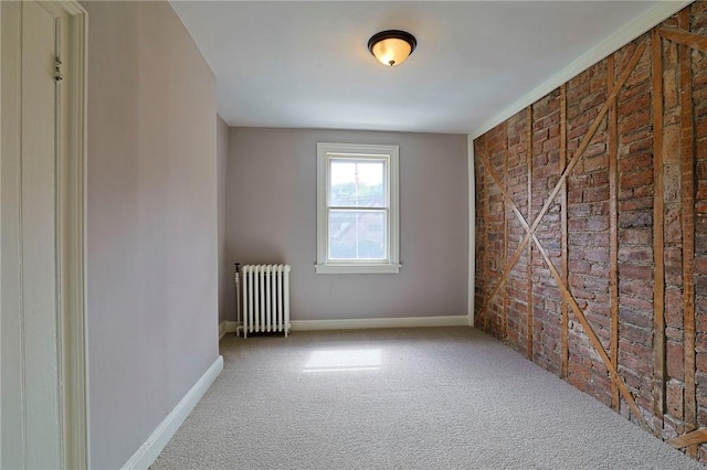 carpeted empty room with radiator heating unit and brick wall