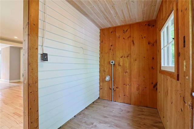 interior space with wood walls, light wood-type flooring, and wooden ceiling