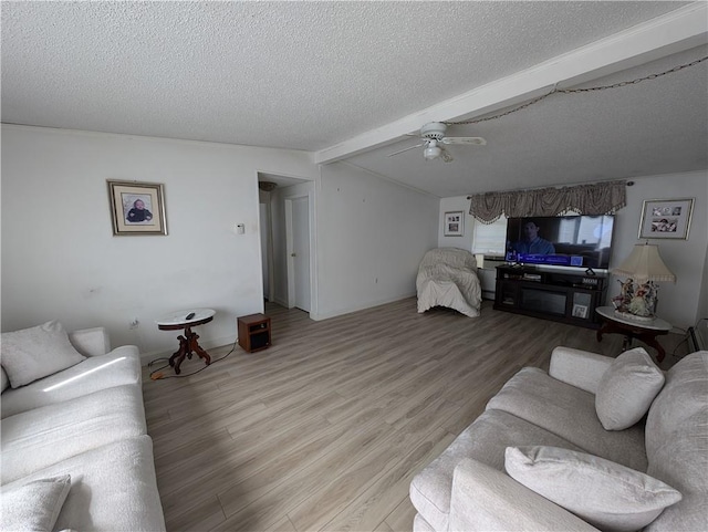 living room featuring ceiling fan, beamed ceiling, light hardwood / wood-style floors, and a textured ceiling