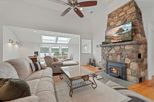 living room with ceiling fan, a fireplace, light hardwood / wood-style flooring, and vaulted ceiling