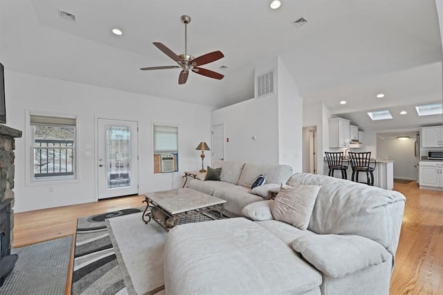 living room featuring ceiling fan, light wood-type flooring, and vaulted ceiling