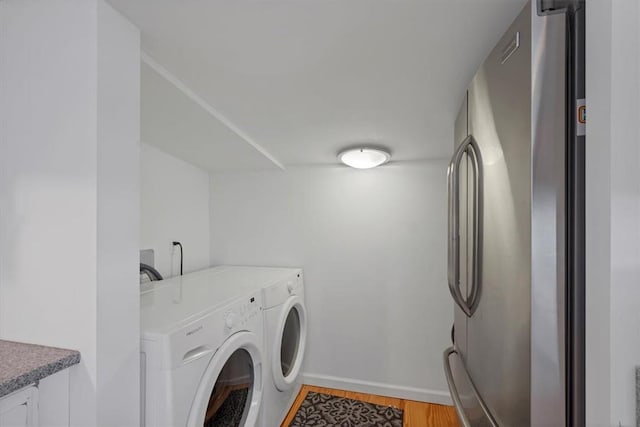 clothes washing area featuring light wood-type flooring and washer and clothes dryer