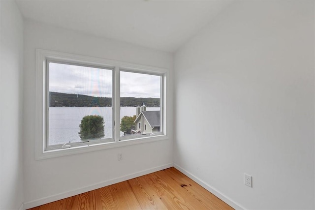 unfurnished room with a water view and wood-type flooring