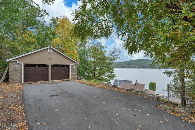 view of property exterior with a water and mountain view, an outdoor structure, and a garage