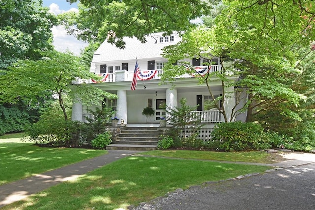 view of front of house featuring covered porch, a balcony, and a front lawn