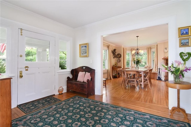 entrance foyer featuring wood-type flooring, an inviting chandelier, and ornamental molding