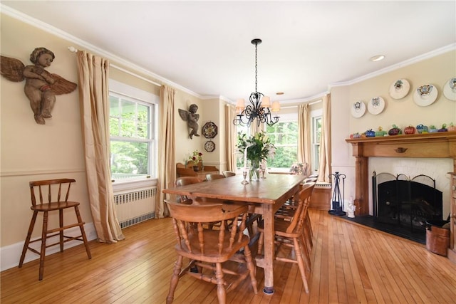 dining space featuring a chandelier, light hardwood / wood-style flooring, radiator, and crown molding