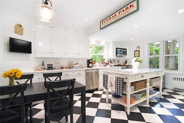 kitchen featuring radiator, decorative light fixtures, a kitchen island, white cabinetry, and stainless steel appliances