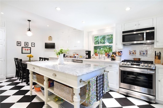 kitchen with sink, white cabinetry, stainless steel appliances, and hanging light fixtures