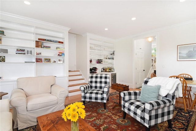 living room with built in features, hardwood / wood-style floors, and ornamental molding