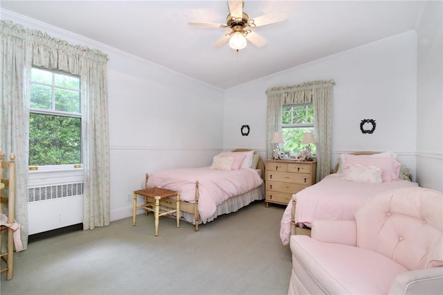 bedroom with radiator heating unit, carpet floors, multiple windows, and ceiling fan