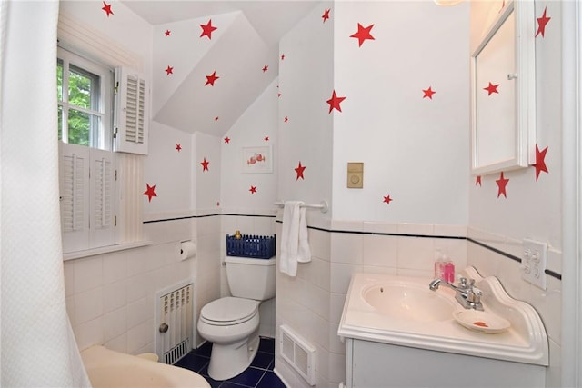 bathroom featuring radiator heating unit, tile patterned flooring, toilet, vanity, and tile walls