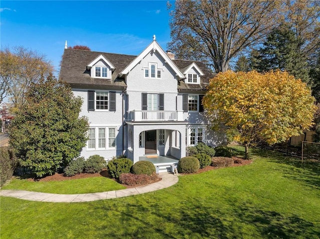 view of front of property with a balcony and a front lawn