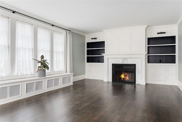 unfurnished living room featuring a premium fireplace, built in features, dark hardwood / wood-style floors, and ornamental molding