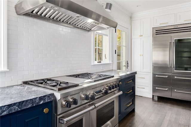 kitchen featuring white cabinets, blue cabinets, high quality appliances, and wall chimney range hood