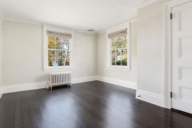 spare room featuring dark hardwood / wood-style flooring, a wealth of natural light, radiator heating unit, and crown molding