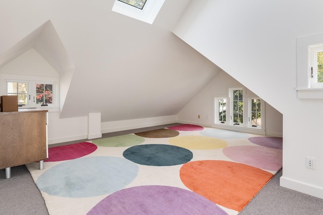 interior space with a wealth of natural light, light carpet, and lofted ceiling with skylight