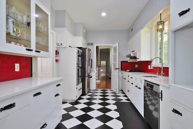 kitchen featuring decorative backsplash, white cabinetry, hanging light fixtures, and appliances with stainless steel finishes