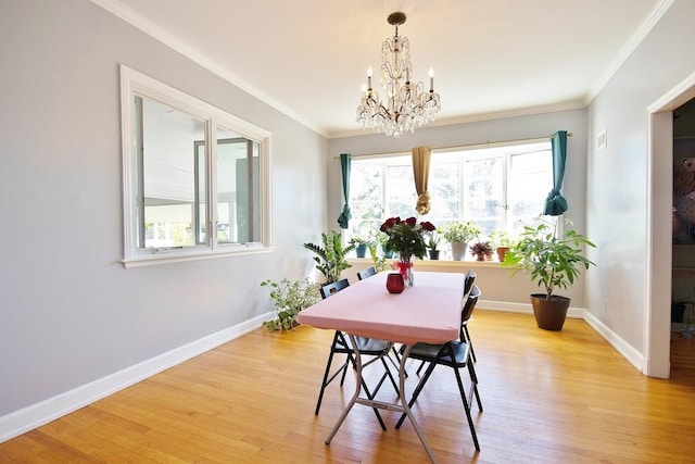 dining area with crown molding, light hardwood / wood-style floors, and an inviting chandelier