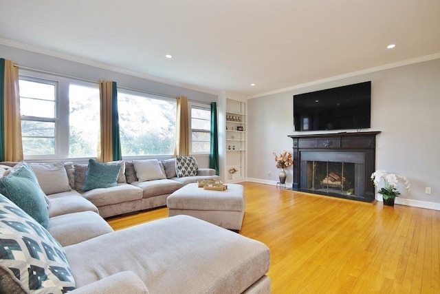 living room with hardwood / wood-style floors, built in features, and crown molding