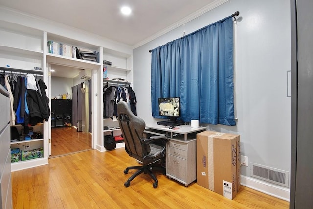 office area with light hardwood / wood-style floors, a wall unit AC, and crown molding