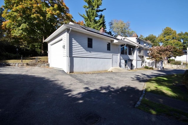 view of side of property featuring solar panels and a garage