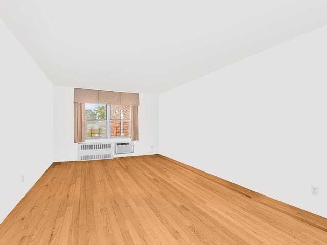 unfurnished living room featuring a wall mounted air conditioner, radiator heating unit, and light wood-type flooring