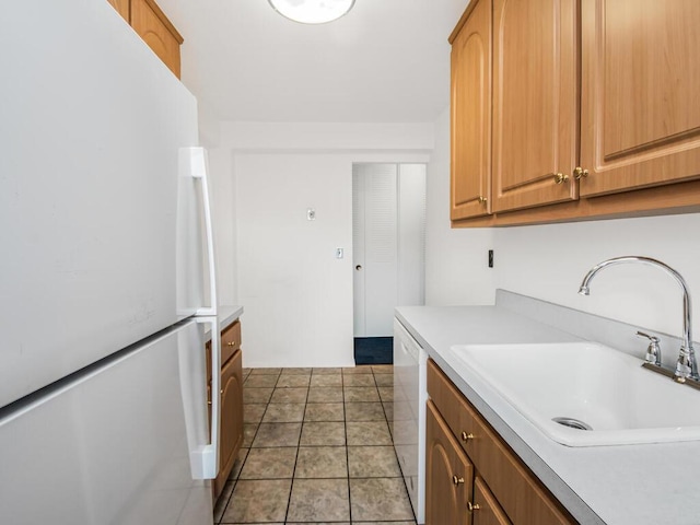 kitchen featuring tile patterned floors, white appliances, and sink