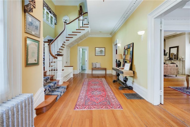 entrance foyer featuring radiator, crown molding, and hardwood / wood-style flooring