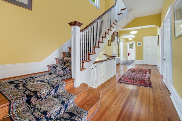 entrance foyer with a towering ceiling, wood-type flooring, and an inviting chandelier