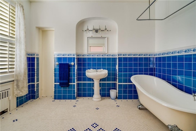 bathroom featuring tile patterned flooring, a bathtub, and tile walls