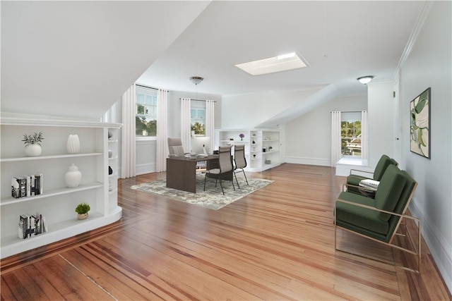 interior space with built in features, light wood-type flooring, crown molding, and lofted ceiling with skylight