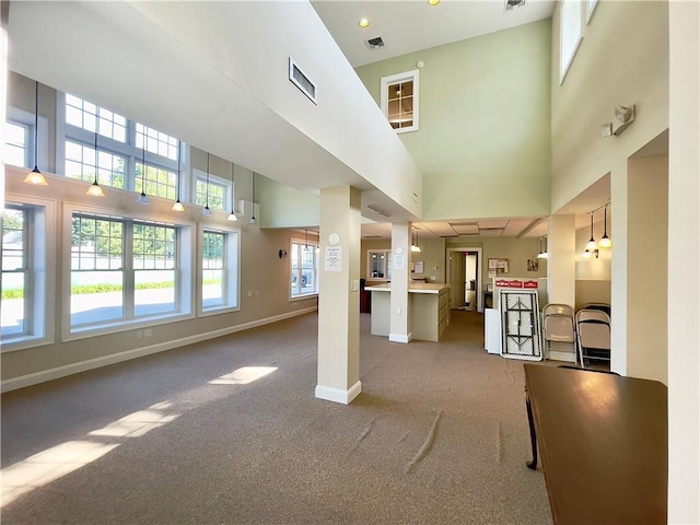 unfurnished living room featuring carpet flooring and a towering ceiling