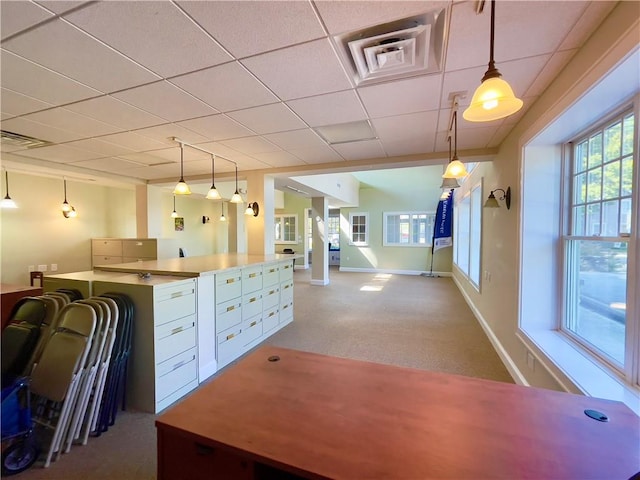 kitchen with carpet flooring, a paneled ceiling, white cabinetry, and hanging light fixtures