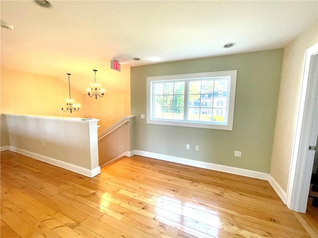 empty room featuring light wood-type flooring and a notable chandelier