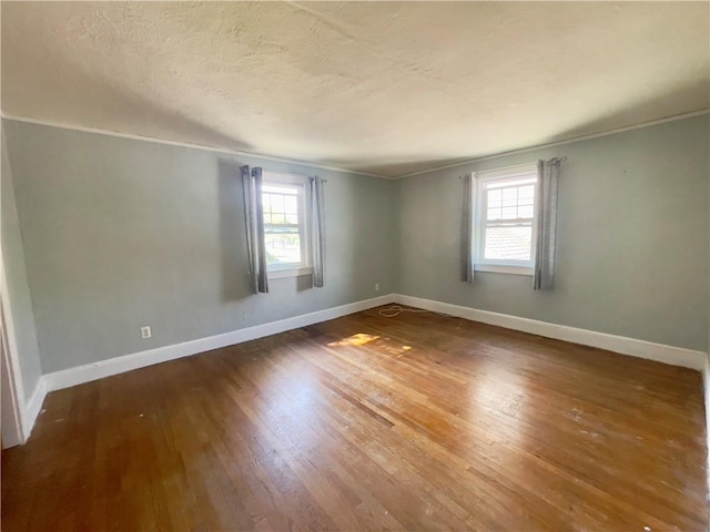 spare room featuring ornamental molding, a healthy amount of sunlight, and wood-type flooring