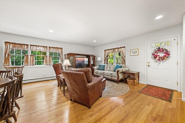 living room featuring light hardwood / wood-style floors, baseboard heating, and a wealth of natural light