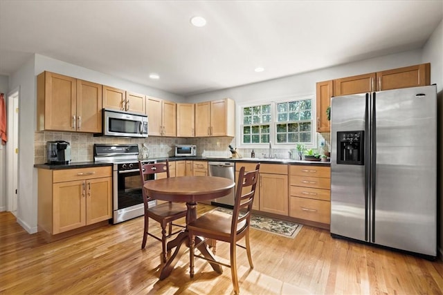 kitchen featuring sink, stainless steel appliances, light hardwood / wood-style flooring, backsplash, and light brown cabinetry