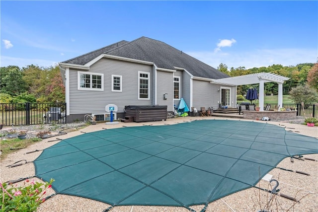 rear view of property featuring a pergola, a patio, and a pool with hot tub