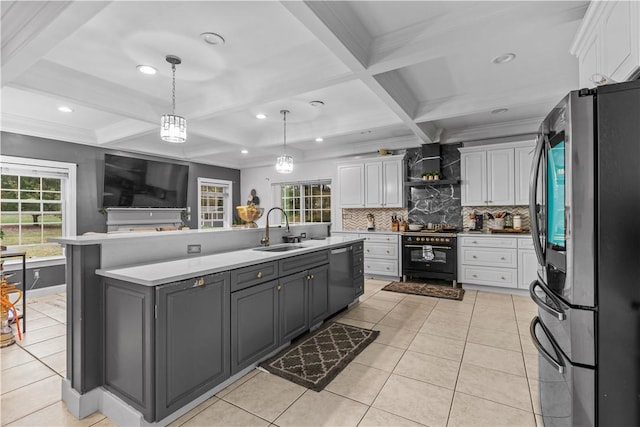 kitchen with appliances with stainless steel finishes, a wealth of natural light, sink, beamed ceiling, and white cabinets